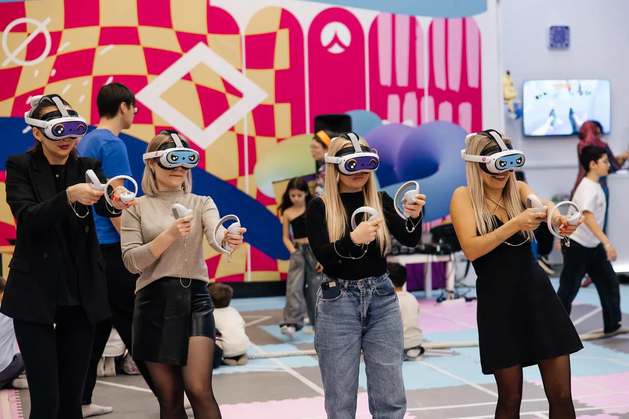 Четыре гостьи в VR-шлемах играют вместе на большой арене